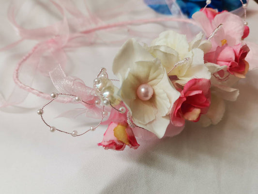 Diadema con flores de tela en tonos rosas, cristal y perlas de imitación.