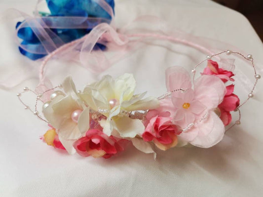 Diadema con flores de tela en tonos rosas, cristal y perlas de imitación.